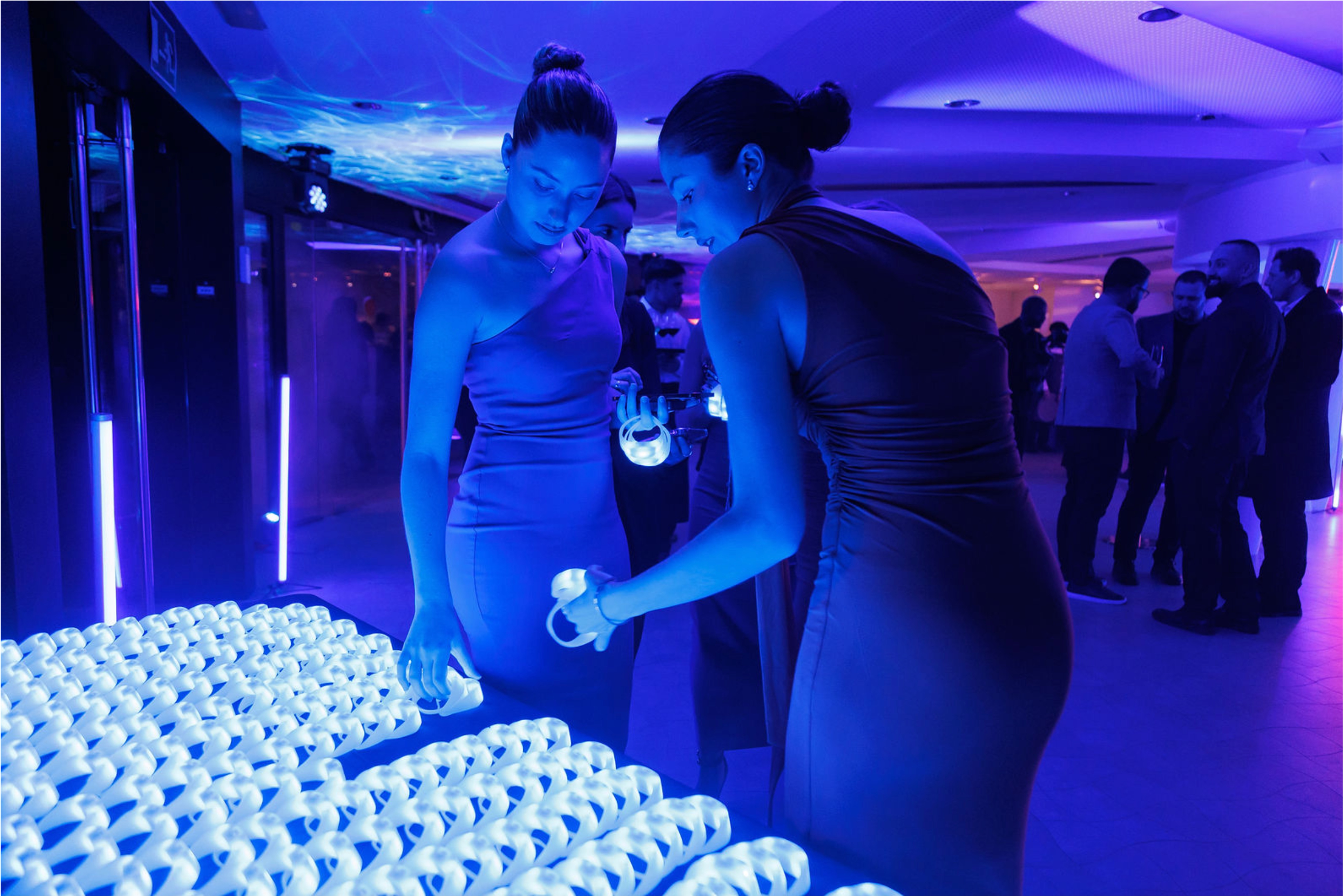 Guests arriving at a high-tech corporate evening event in Barcelona, checking in and receiving glowing LED wristbands.
