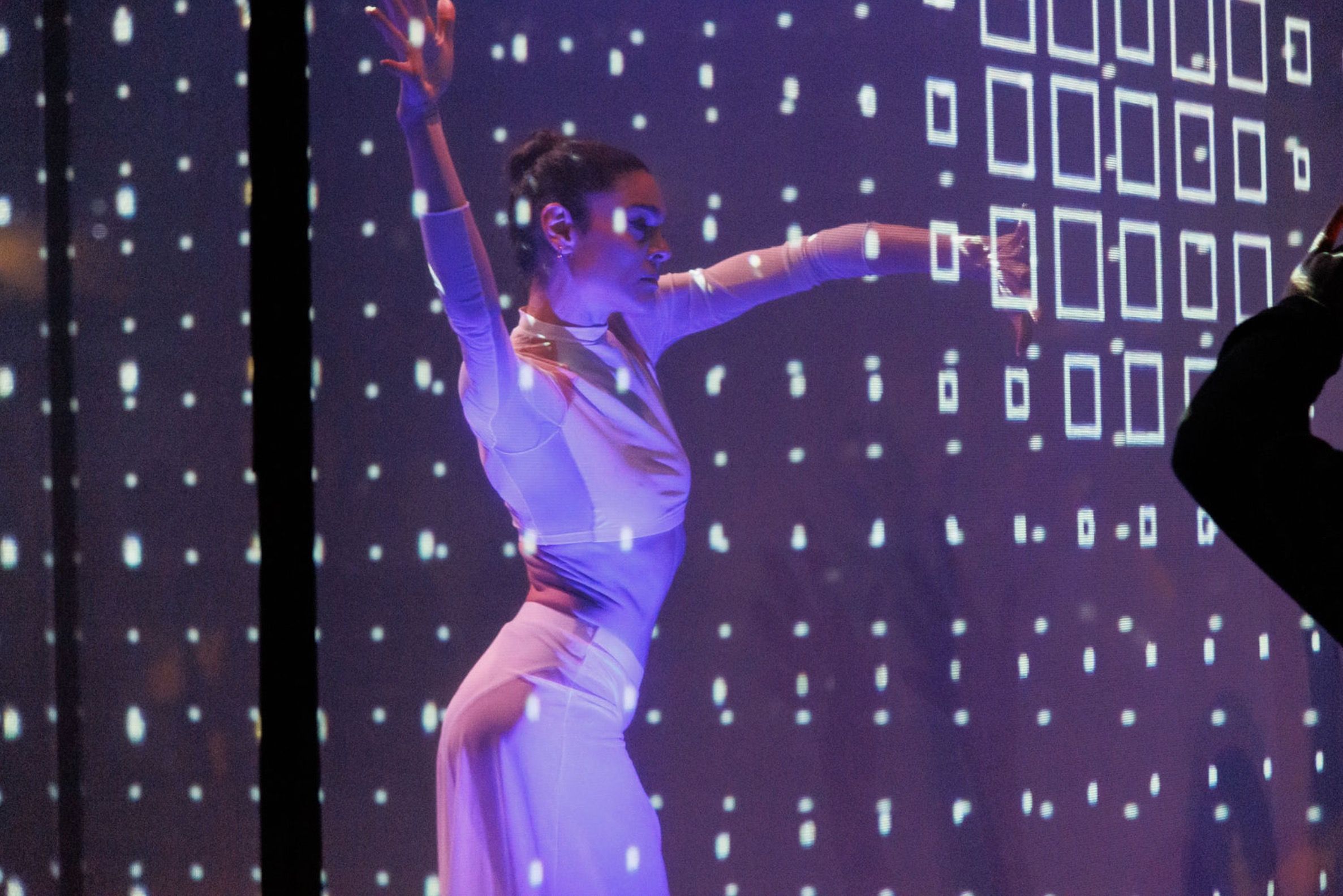 Live performer interacting with a large, projection-mapped digital cube displaying gaming brand assets at an event.