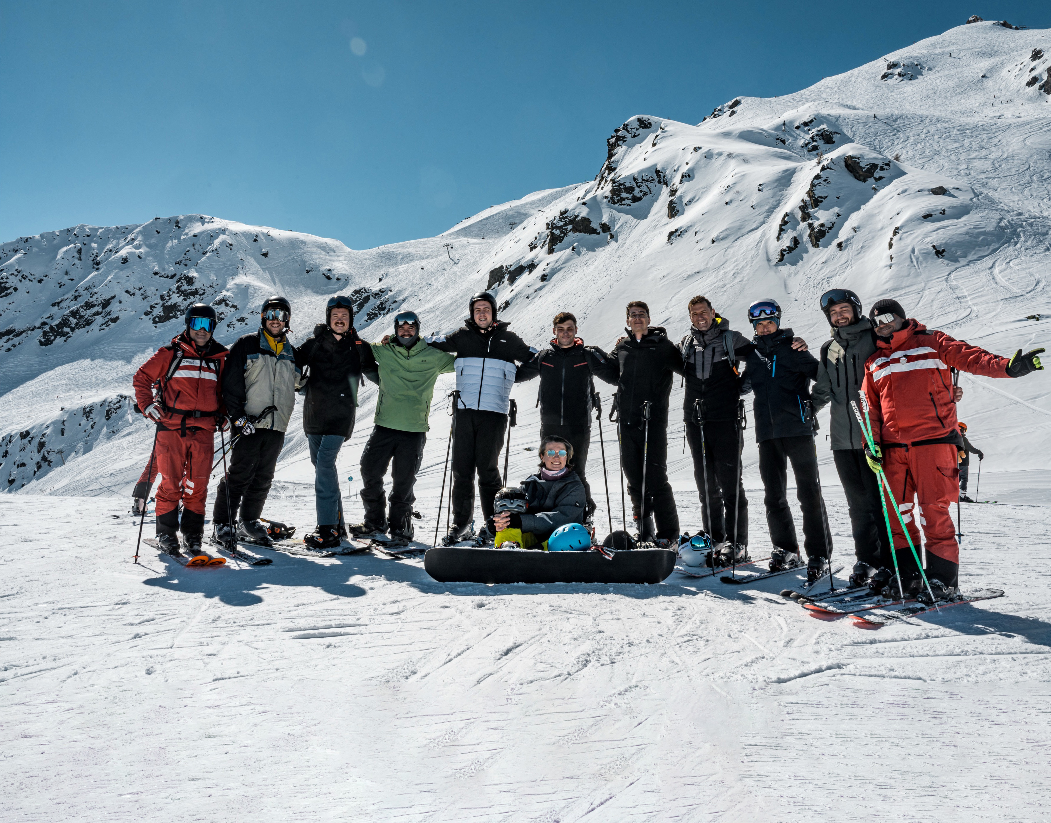 - Group of corporate retreat guests standing together in front of snow-covered Alps in Courchevel